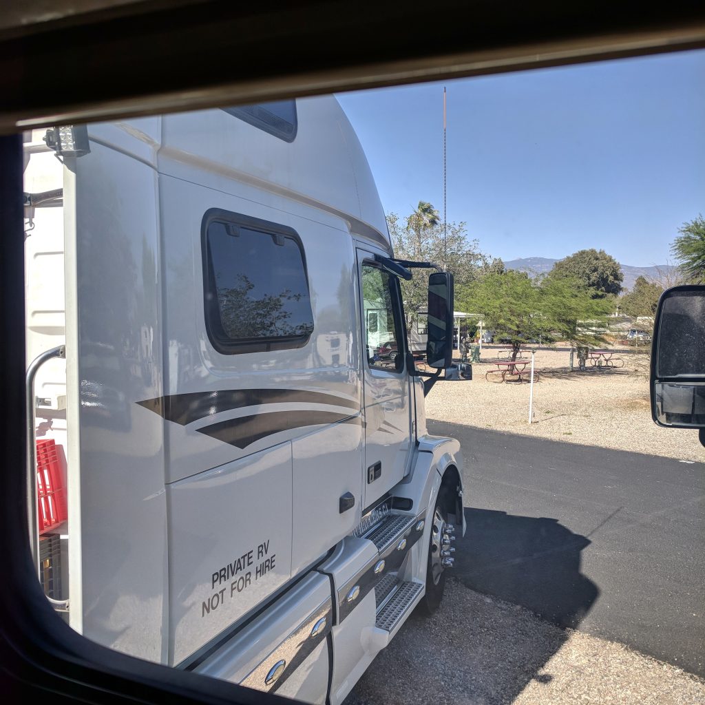 large white semi-truck parked next to a motorhome in an rv park, showing how tight rv campground spaces can be